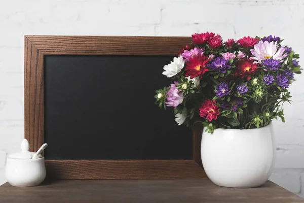 Flowers in vase and blank board — Stock Photo