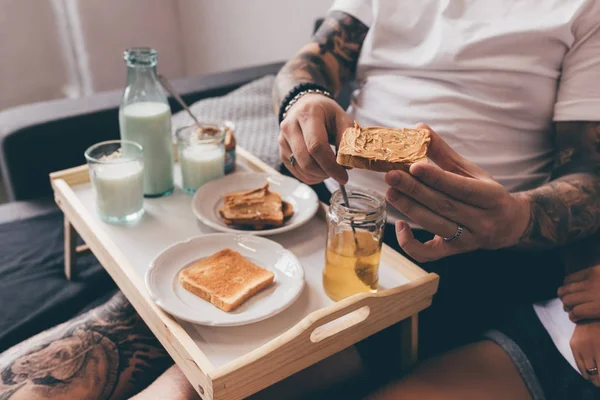 Hombre sosteniendo tostadas con mantequilla de maní - foto de stock