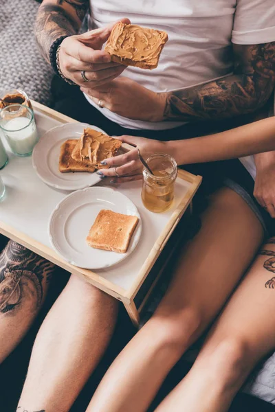 Pareja comiendo tostadas en la cama - foto de stock