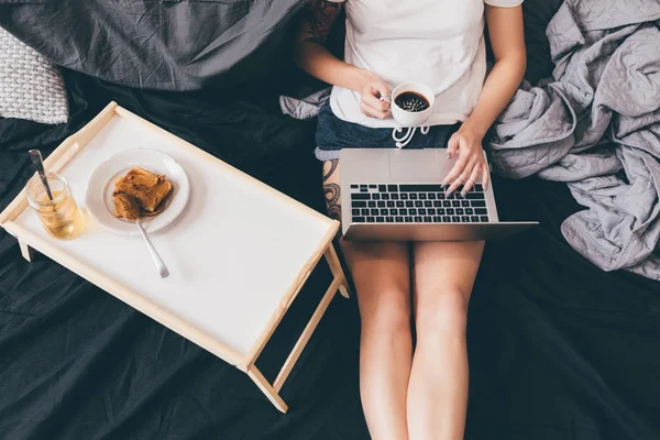 Mujer con portátil en la cama - foto de stock