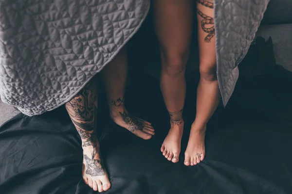 Татуированная пара, покрытая одеялом — стоковое фото