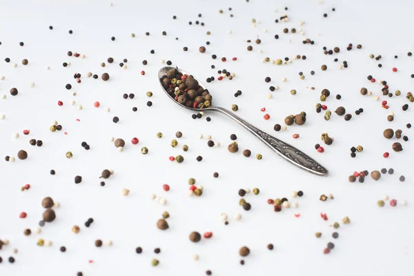 Spoon with spilled peppercorns — Stock Photo