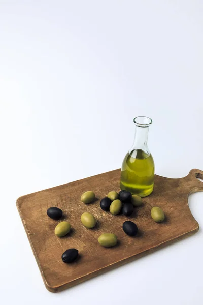 Bottle of olive oil and olives on board — Stock Photo