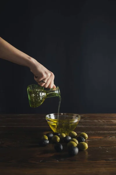 Donna versando olio da bottiglia a ciotola — Foto stock