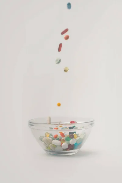 Pilules tombant dans un bol en verre — Photo de stock