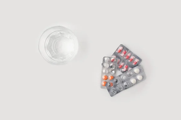 Plaquettes thermoformées contenant des pilules et un verre d'eau — Photo de stock