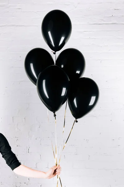 Person holding black balloons — Stock Photo