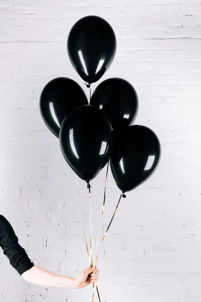 Persona sosteniendo globos negros - foto de stock