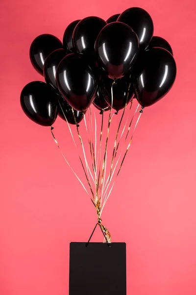 Shopping bag hanging on black balloons — Stock Photo