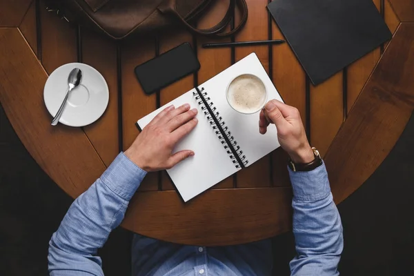 Hombre con bloc de notas bebiendo café - foto de stock