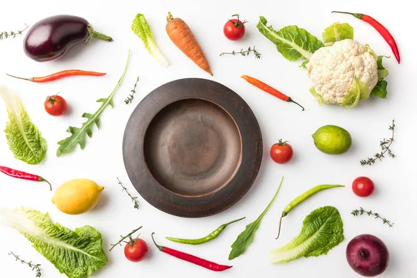 Plate among uncooked vegetables — Stock Photo