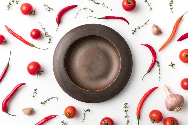 Plate among chili peppers and tomatoes — Stock Photo