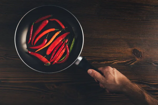 Man holding pan with chili peppers — Stock Photo