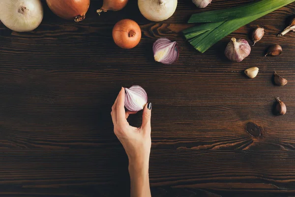 Frau hält halbe Zwiebel in der Hand — Stockfoto