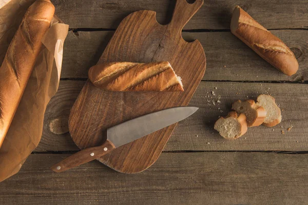 Baguettes, cuchillo y tabla de cortar - foto de stock