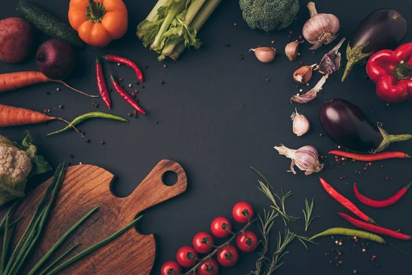 Top view of different vegetables and cutting board on a table — Stock Photo