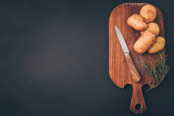 Top view of wooden board with raw potatoes on gray table — Stock Photo