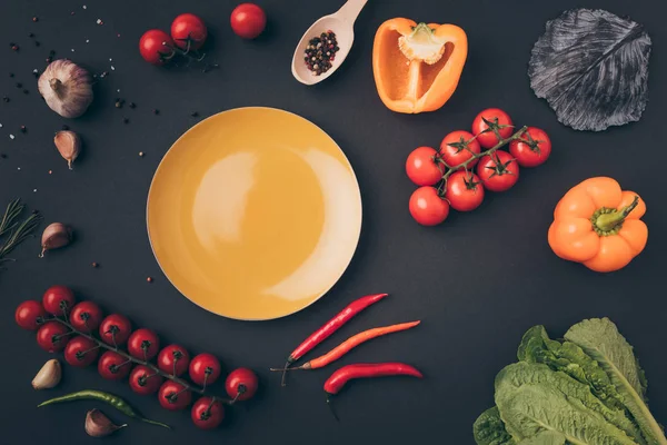 Vue du dessus des poivrons et tomates cerises avec assiette jaune sur table grise — Photo de stock