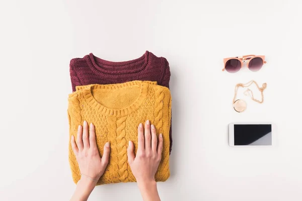 Hands with sweaters, accessories and smartphone — Stock Photo