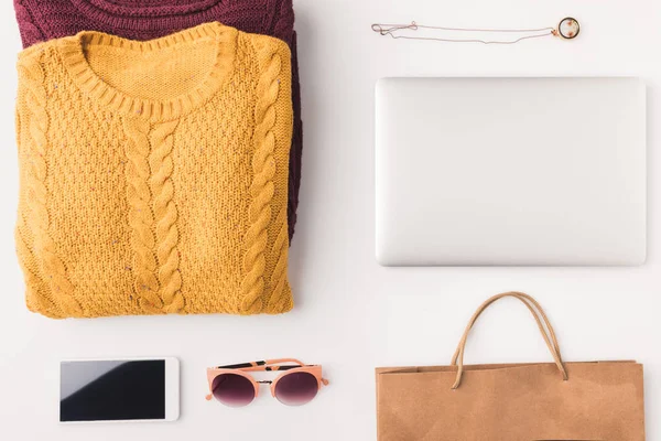 Sweaters, laptop, smartphone and shopping bag — Stock Photo