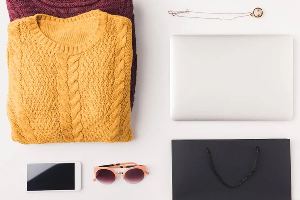 Sweaters, laptop, smartphone and shopping bag — Stock Photo