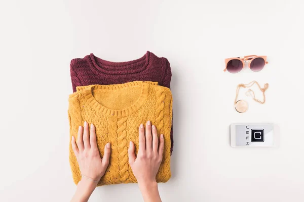 Sweaters and smartphone with uber appliance — Stock Photo