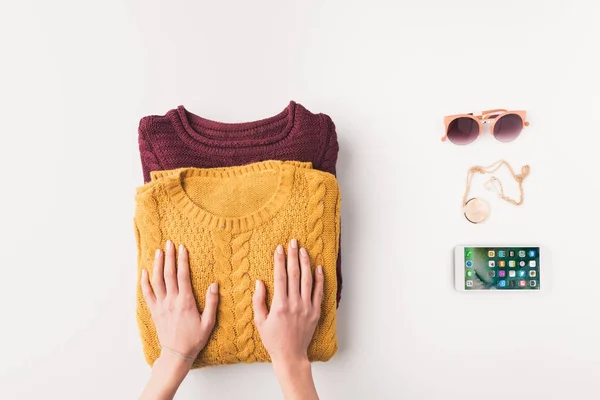 Руки со свитерами и iphone — стоковое фото