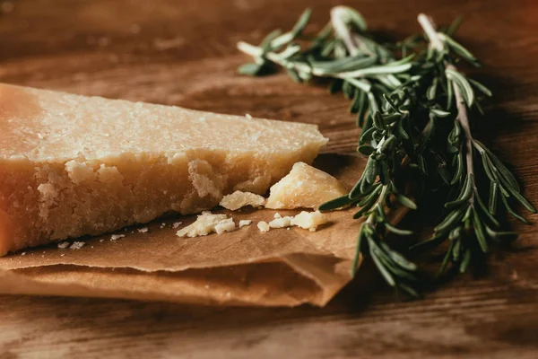 Close-up de queijo parmesão e alecrim fresco em mesa de madeira — Fotografia de Stock