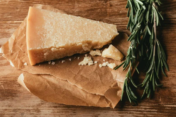 Top view of Parmesan cheese and fresh rosemary on wooden tabletop — Stock Photo