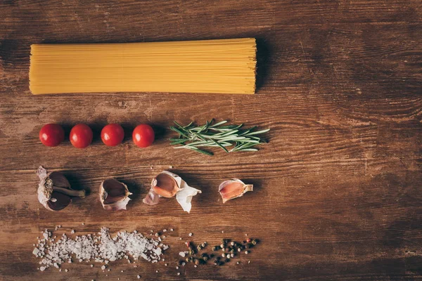 Acostado plano con pasta de fila e ingredientes frescos en la mesa de madera - foto de stock