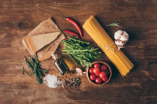 Top view of traditional row pasta and fresh ingredients on wooden tabletop — Stock Photo