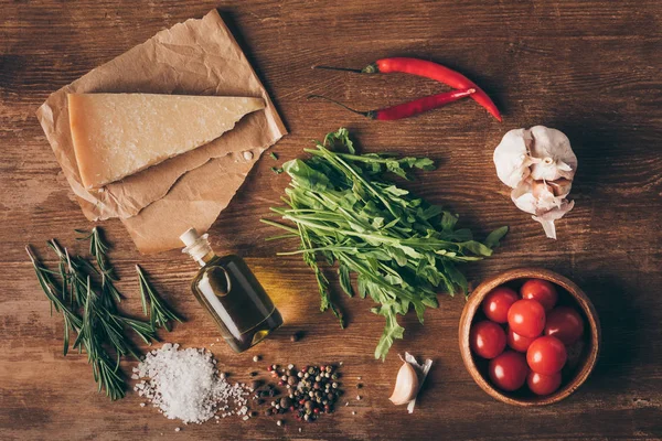 Vista superior de parmesão, óleo e ingredientes frescos na mesa de madeira — Fotografia de Stock