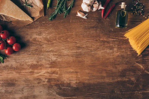 Вид зверху рядок макаронних виробів та свіжих інгредієнтів на дерев'яному столі з місцем для тексту — стокове фото