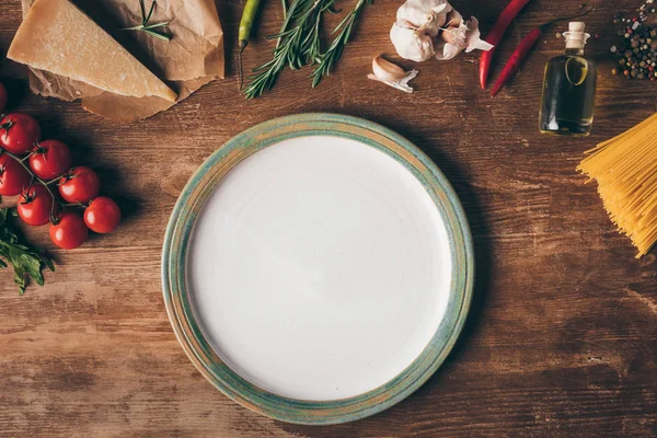 Vista superior de massa de linha, ingredientes frescos e prato na mesa de madeira — Fotografia de Stock