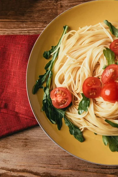 Vista superior de la pasta italiana tradicional con tomates y rúcula en plato - foto de stock