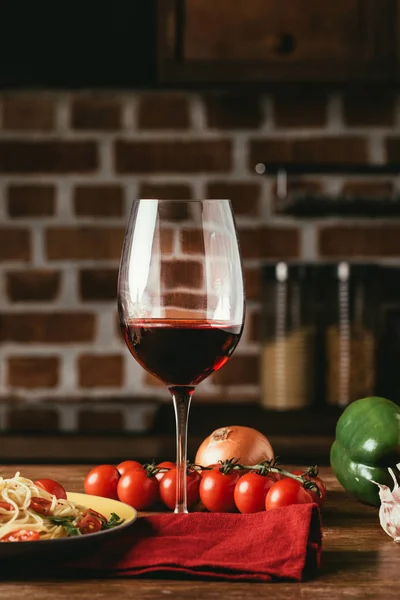 Pasta italiana tradicional con tomates y rúcula en plato y copa de vino tinto - foto de stock