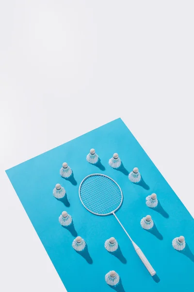 Vista de ángulo alto de raqueta de bádminton y volantes en papel azul, aislado en blanco - foto de stock