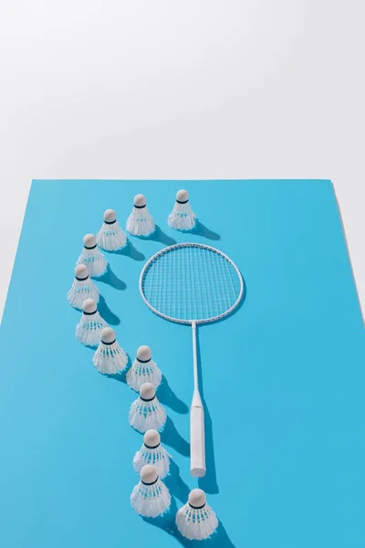 High angle view of badminton racket and shuttlecocks on blue paper, isolated on white — Stock Photo