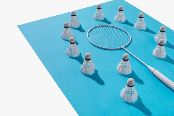 Vista de ángulo alto de raqueta de bádminton y volantes en papel azul, aislado en blanco - foto de stock