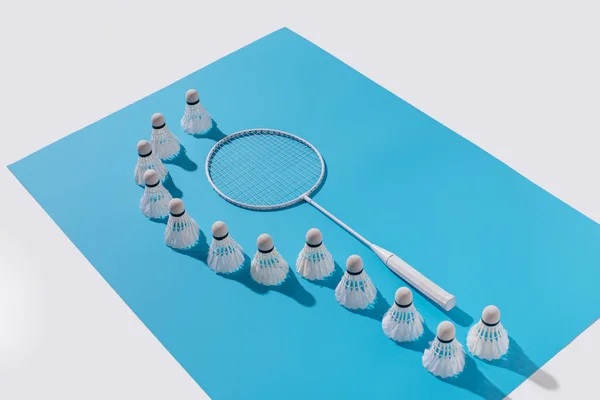 Vista de ángulo alto de raqueta de bádminton y volantes sobre papel azul - foto de stock