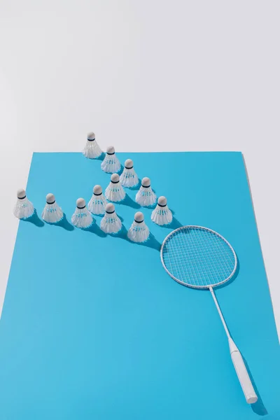 Composizione con racchetta da badminton bianca e navette su carta blu — Foto stock