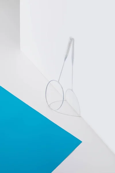 Badminton racket at white wall with blue paper near — Stock Photo