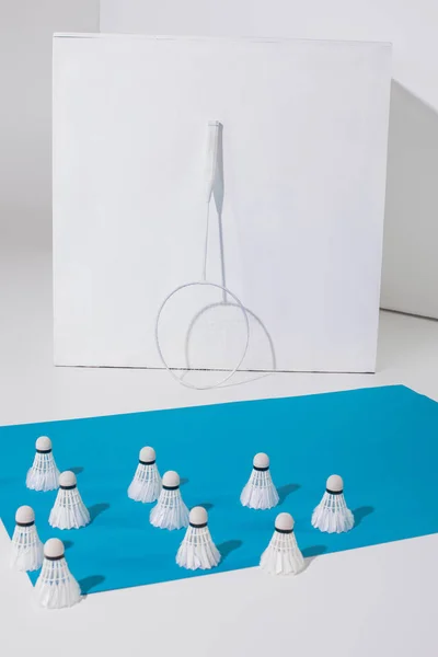 Raquete de badminton no cubo branco e shuttlecocks no papel azul — Fotografia de Stock