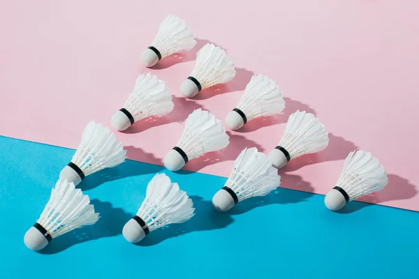 Vue de dessus de la composition avec des navettes de badminton sur bleu et rose — Photo de stock