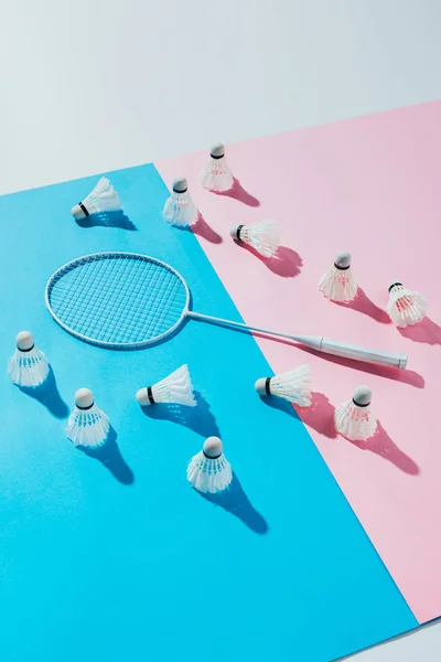 Trasbordadores alrededor de raqueta de bádminton en papeles azules y rosados - foto de stock