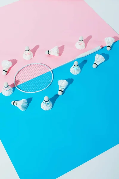 Shuttlecocks around badminton racket on blue and pink papers — Stock Photo