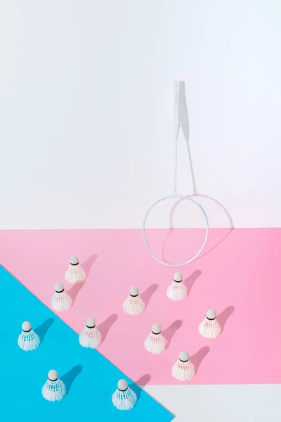 Badminton racket and shuttlecocks on blue and pink papers at wall — Stock Photo