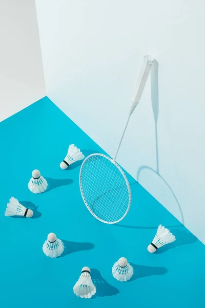 Badminton racket and shuttlecocks on blue paper at white wall — Stock Photo