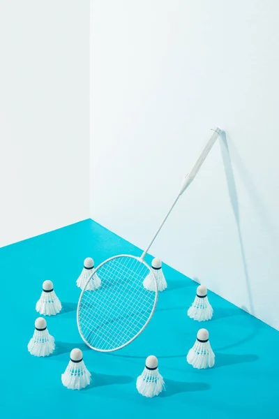 Circle of shuttlecocks around badminton racket on blue paper — Stock Photo