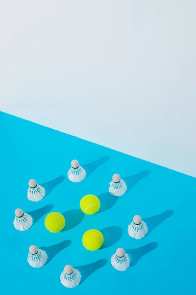 Cercle de navettes de badminton autour des balles de tennis sur bleu — Photo de stock